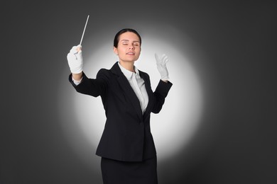 Professional conductor with baton on grey background