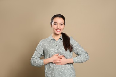 Photo of Happy healthy woman touching her belly on beige background