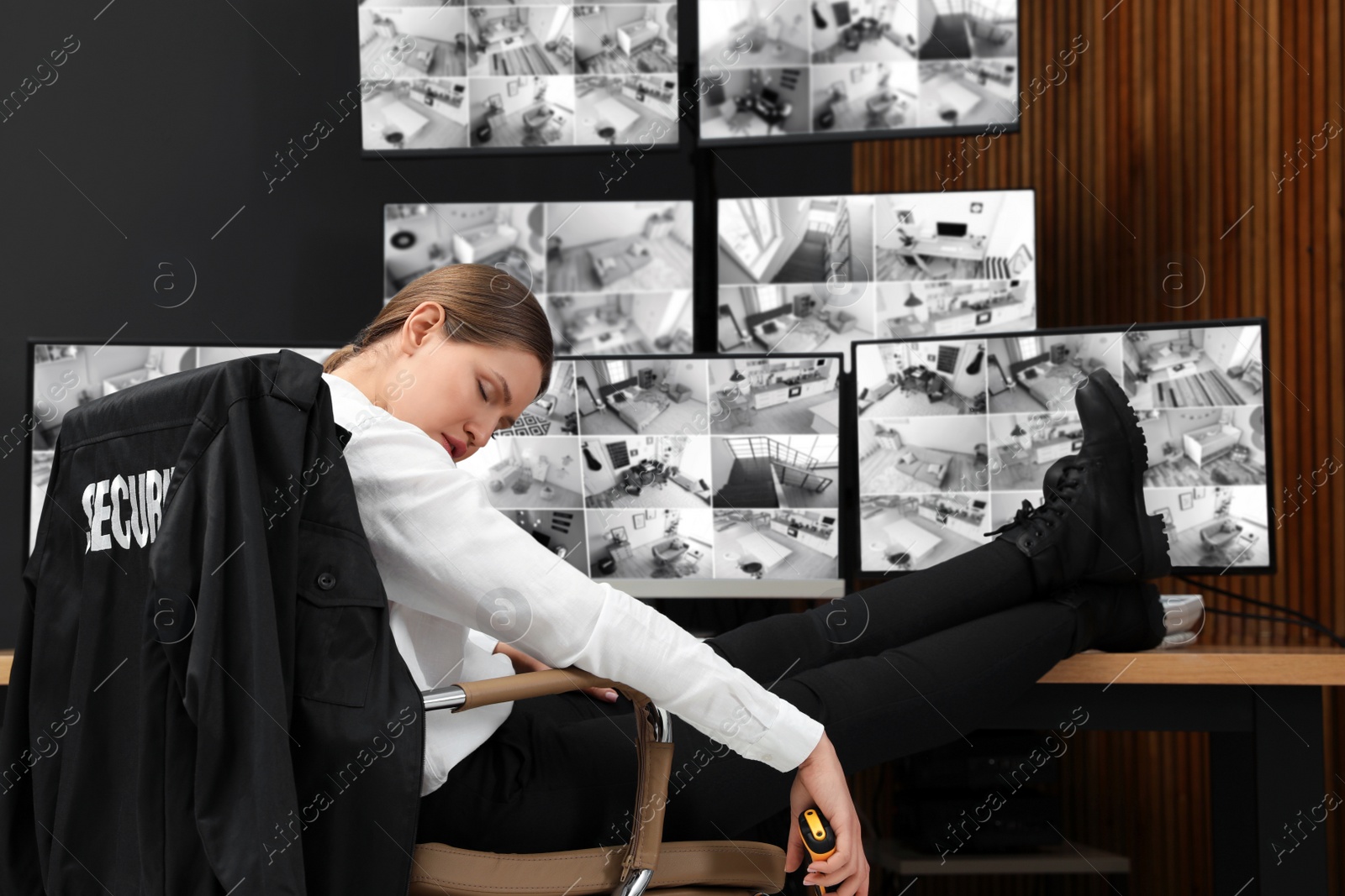 Photo of Tired security guard sleeping at workplace in office