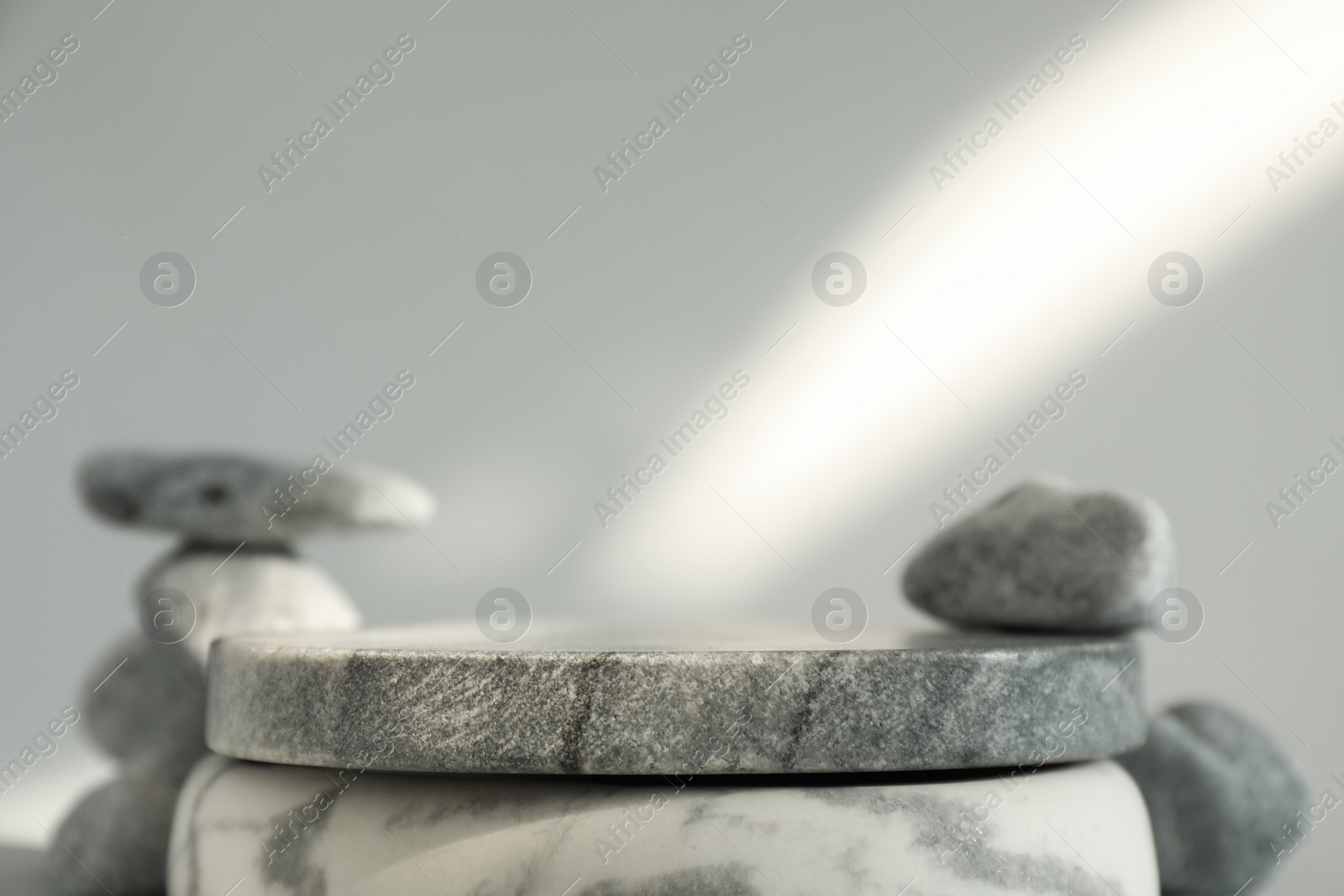 Photo of Presentation for product. Stone podium and pebbles on light grey background. Space for text