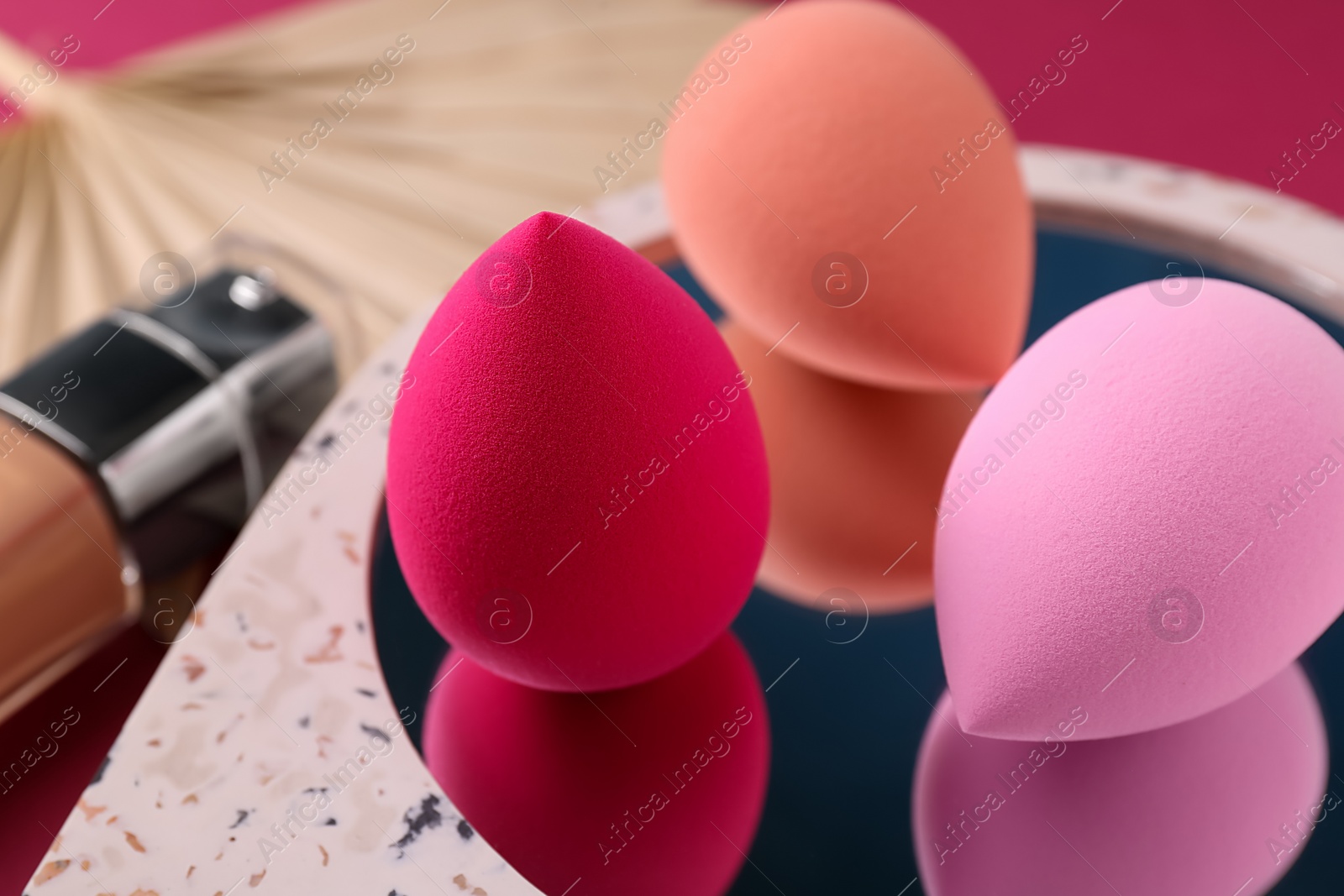 Photo of Stylish presentation of makeup sponges on pink background, closeup