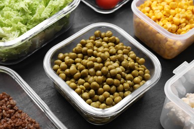 Photo of Plastic and glass containers with different fresh products on black table, closeup