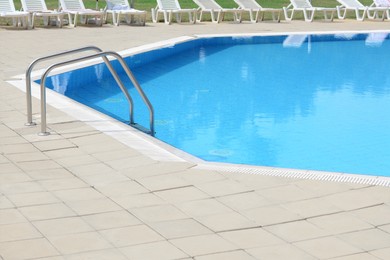 Photo of Outdoor swimming pool with handrails at resort on sunny day