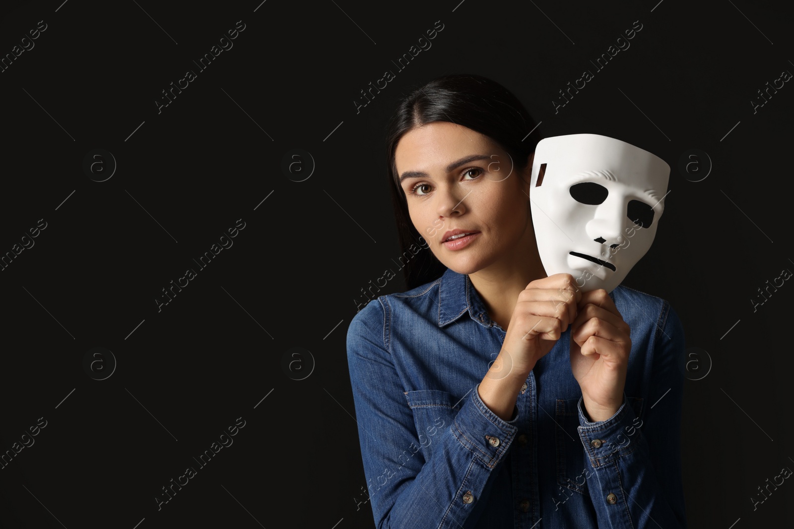 Photo of Multiple personality concept. Woman with mask on black background, space for text