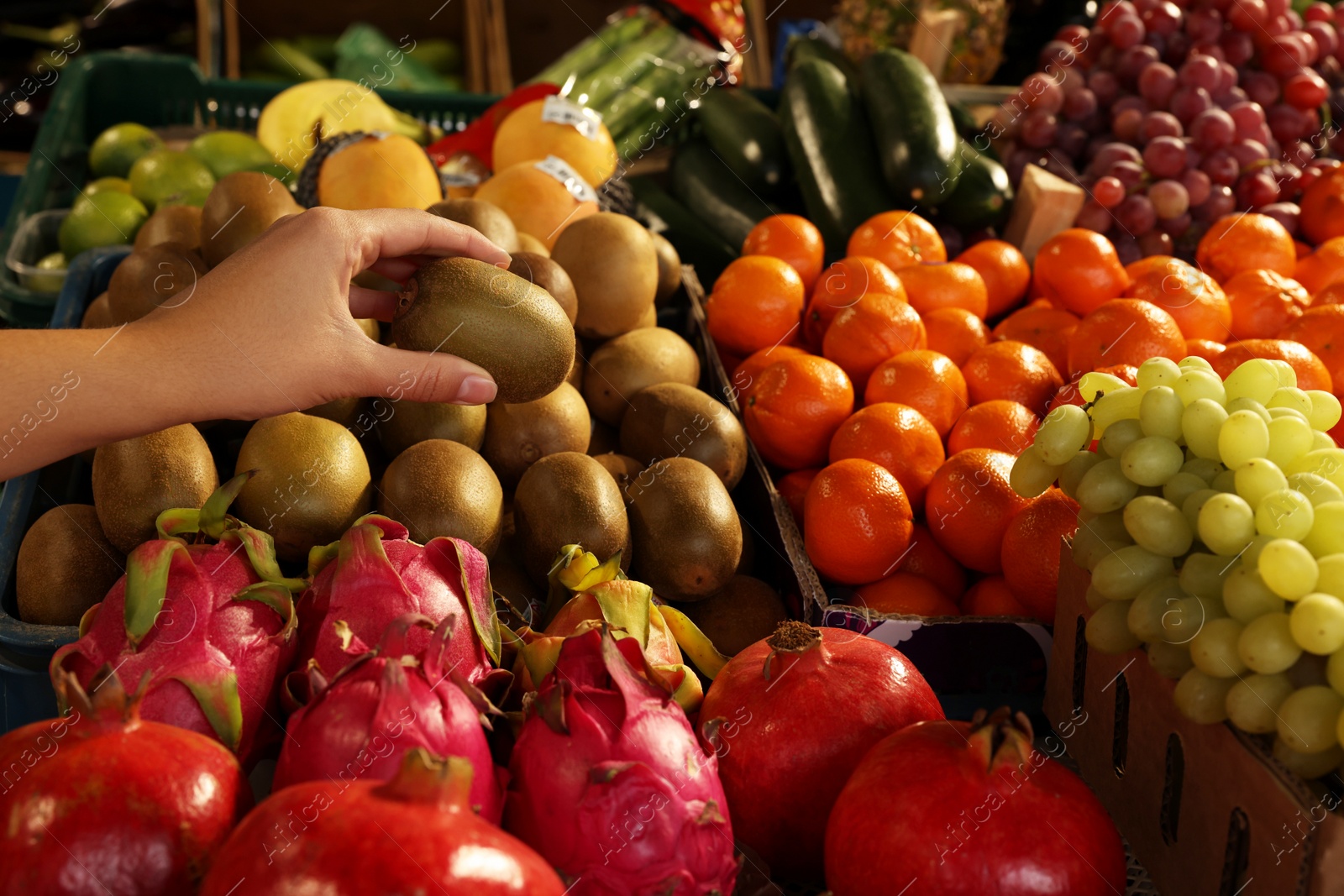 Photo of Woman picking fresh kiwi at market, closeup