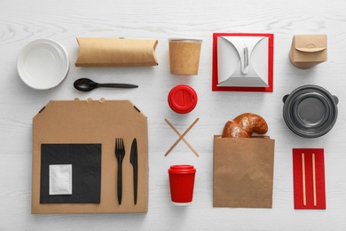 Flat lay composition with paper bag and different takeaway items on wooden background. Space for design