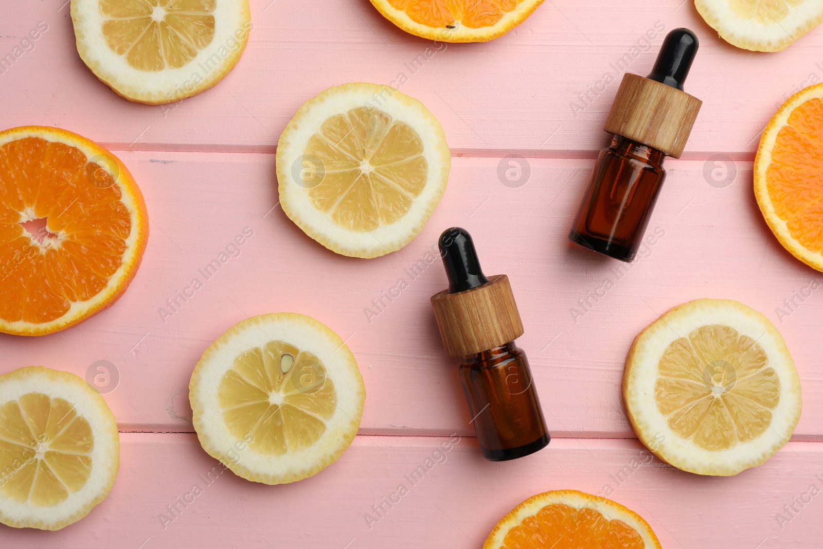 Photo of Aromatherapy. Different essential oils and citrus fruits on pink wooden table, flat lay