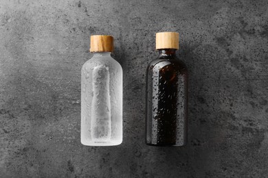 Photo of Bottlescosmetic product on wet grey background, flat lay. Space for text