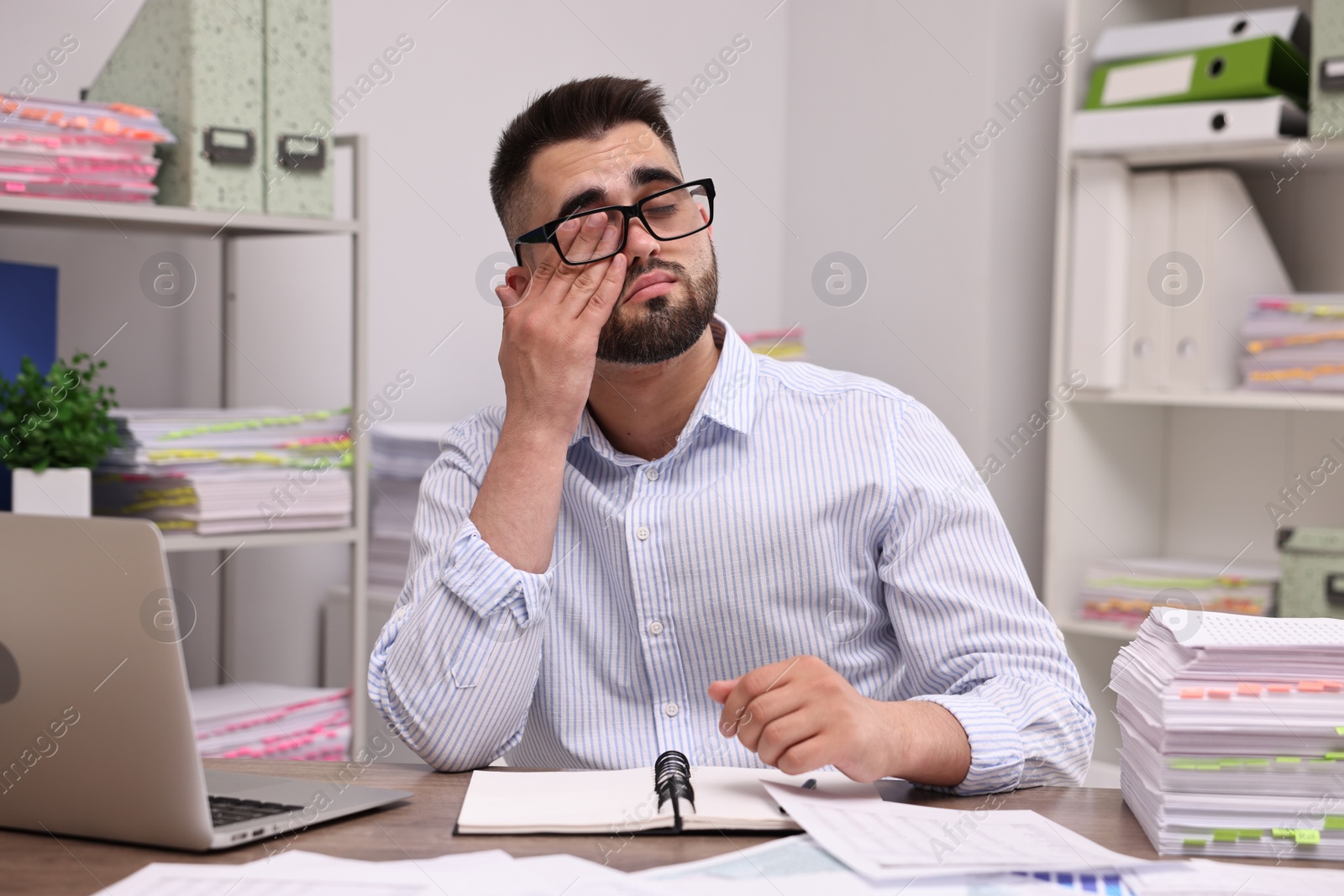 Photo of Overwhelmed man sitting at table in office