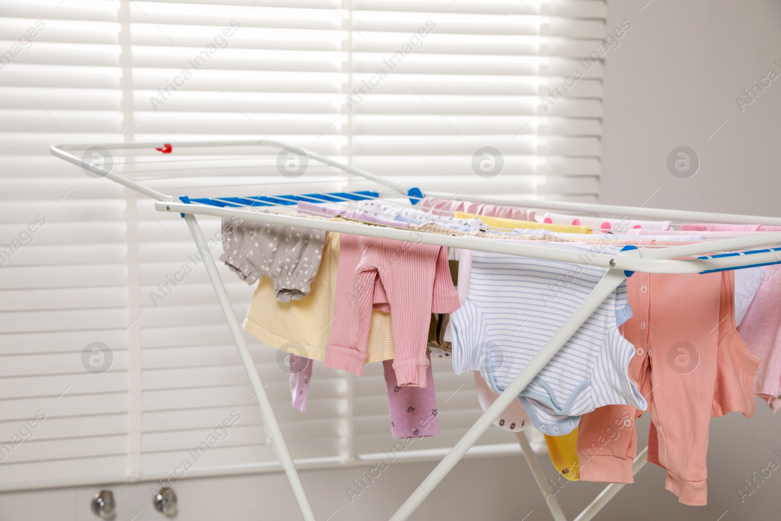 Photo of Clean laundry hanging on drying rack indoors