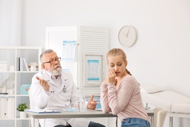 Photo of Coughing young woman visiting doctor at clinic