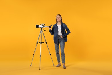 Happy astronomer with telescope on orange background