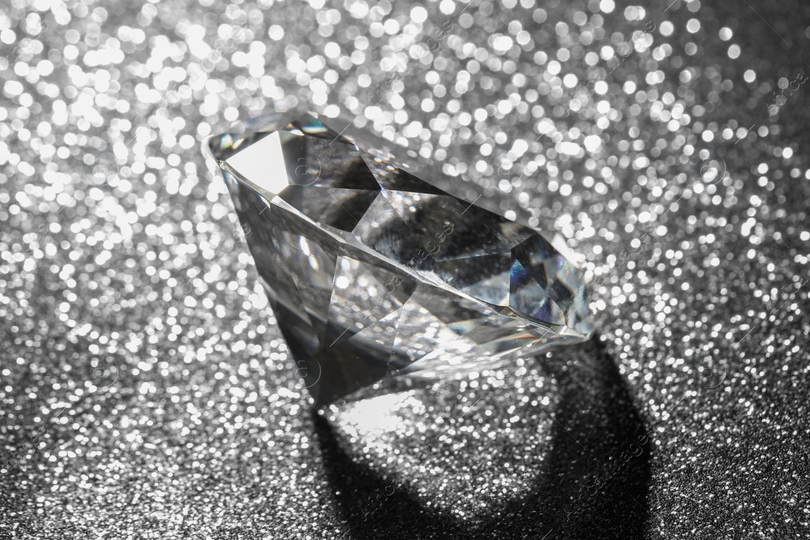 Photo of Beautiful diamond on dark shiny background, closeup