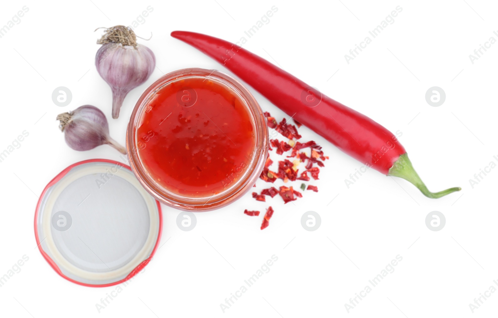 Photo of Spicy chili sauce in glass jar, garlic and pepper isolated on white, top view