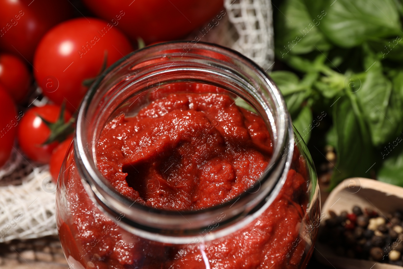 Photo of Jar of tasty tomato paste and ingredients on table, closeup