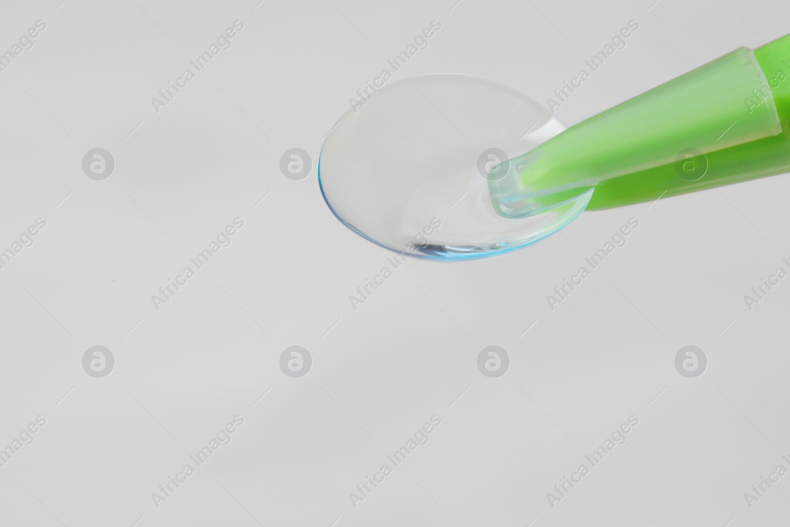 Photo of Tweezers with contact lens on white background, closeup. Space for text