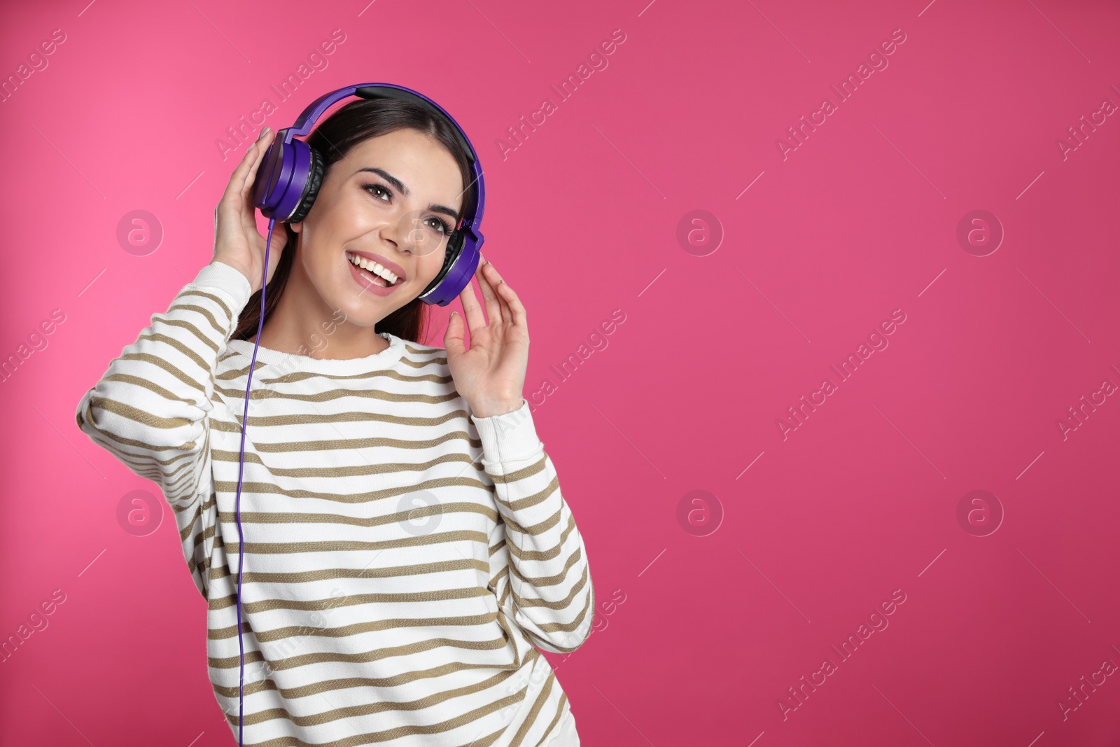 Photo of Attractive young woman enjoying music in headphones on color background. Space for text