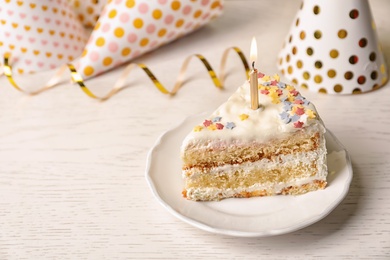 Photo of Slice of delicious birthday cake with candle on table