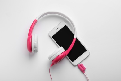 Photo of Stylish headphones and modern phone on white background, top view