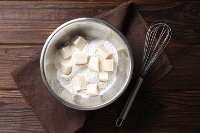 Photo of Making shortcrust pastry. Flour, butter and whisk on wooden table, top view