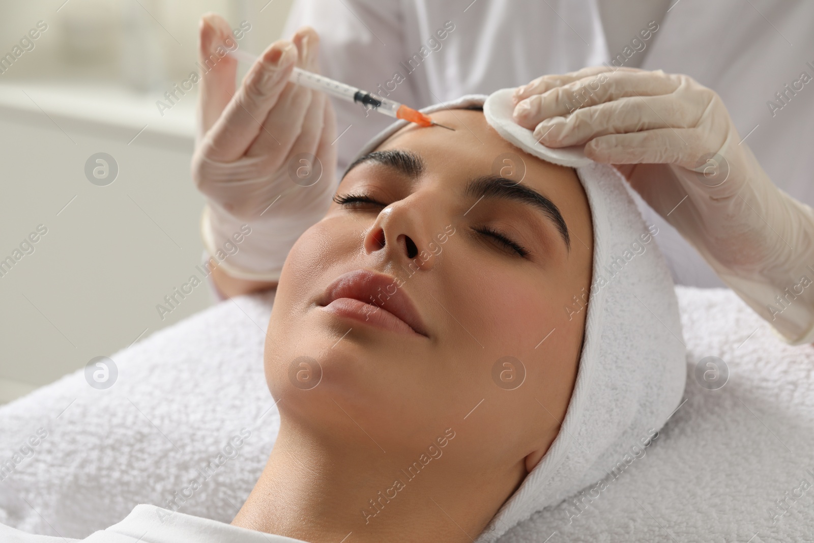 Photo of Doctor giving facial injection to young woman in clinic, closeup. Cosmetic surgery