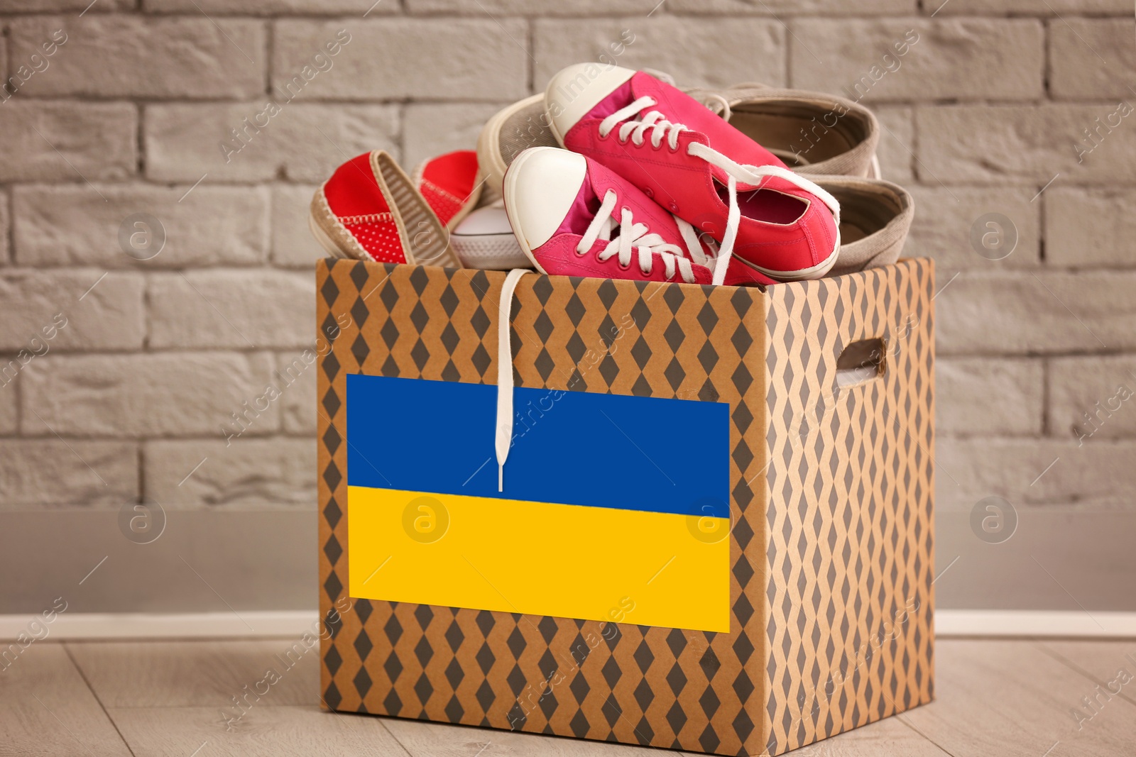 Image of Humanitarian aid for Ukrainian refugees. Donation box with shoes on floor near brick wall