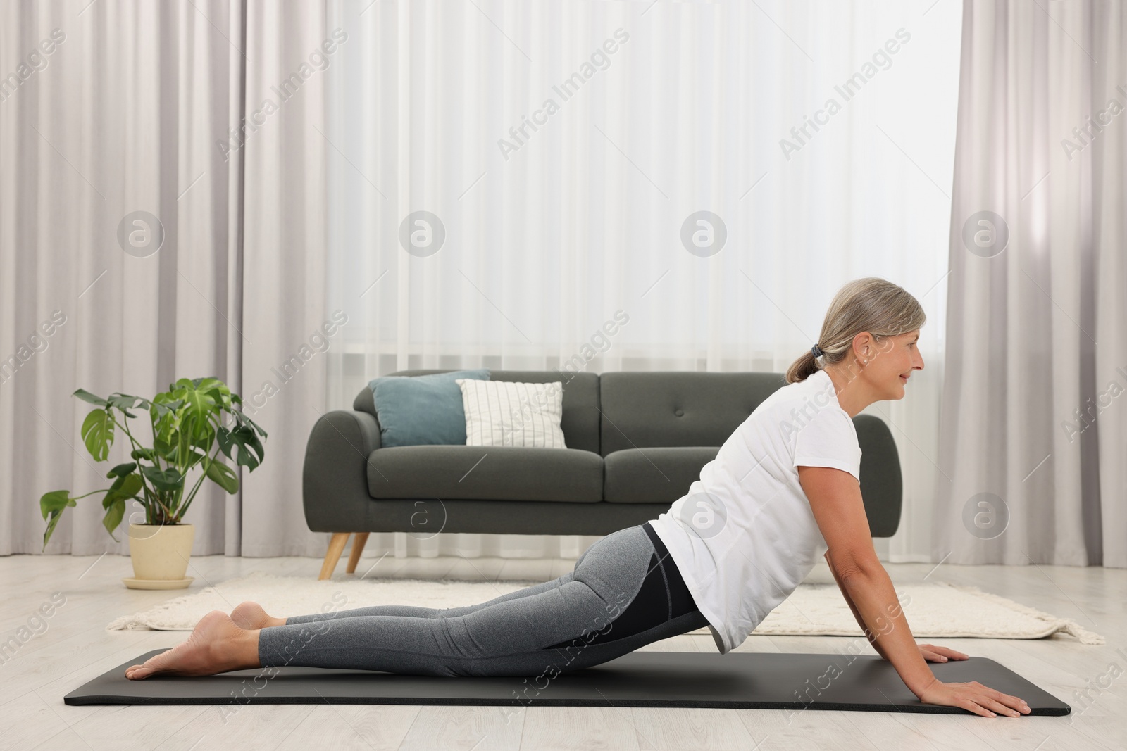 Photo of Senior woman practicing yoga on mat at home