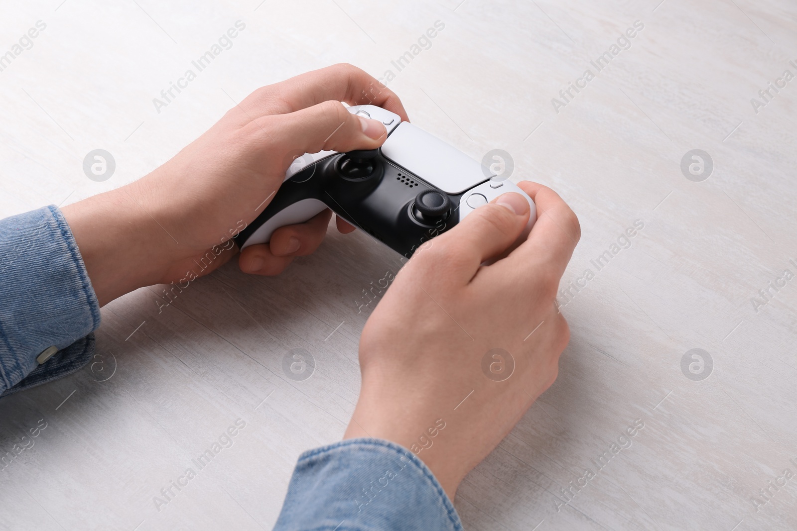 Photo of Man using wireless game controller at white table, closeup