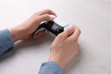 Photo of Man using wireless game controller at white table, closeup