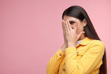 Photo of Embarrassed woman covering face with hands on pink background, space for text