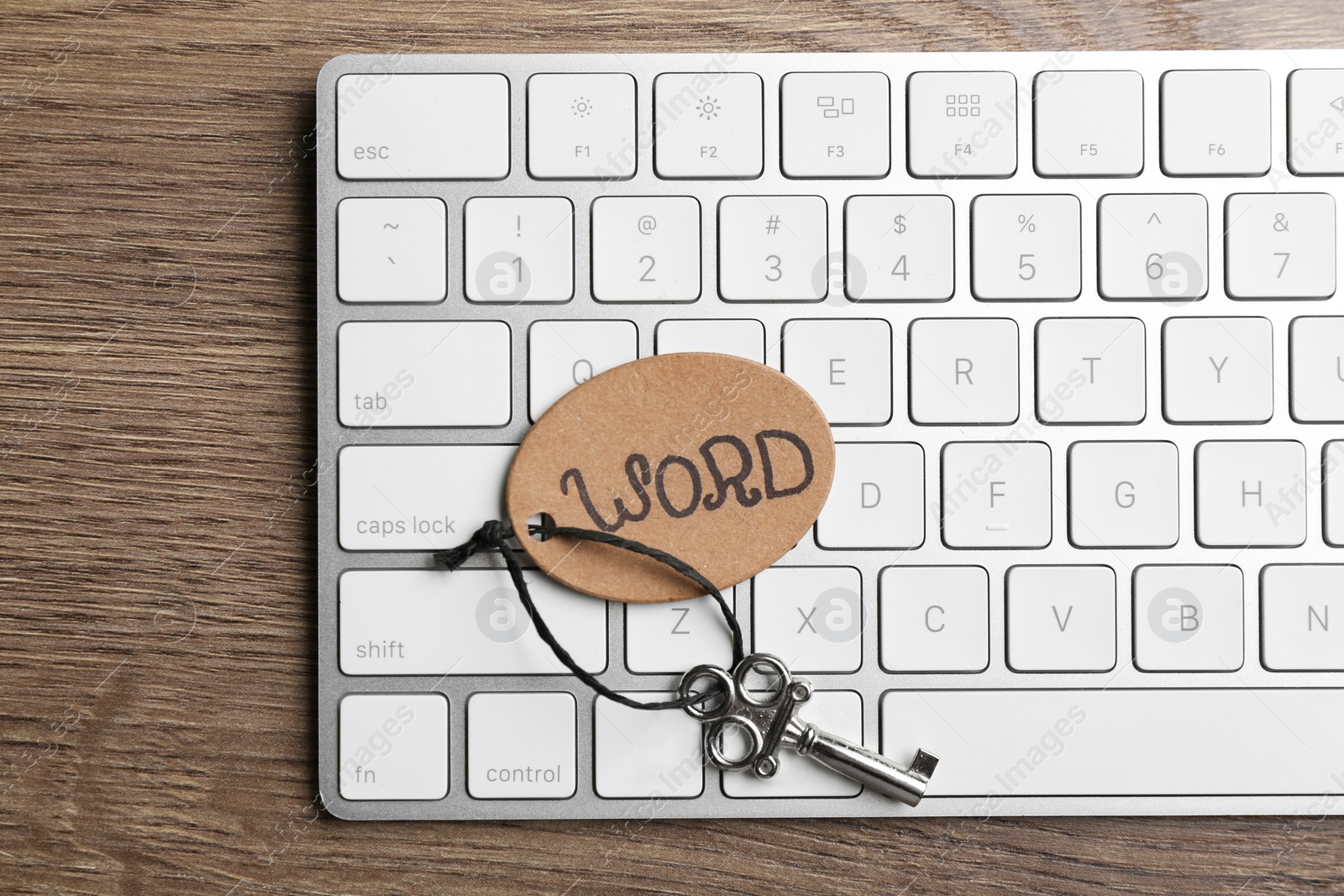 Photo of Vintage key with tag and keyboard on wooden table, top view. Keyword concept