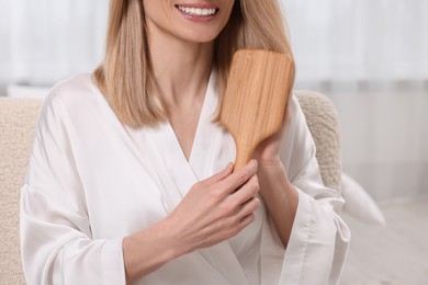 Photo of Woman brushing her hair indoors, closeup view