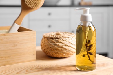 Dispenser with liquid soap, wicker box and brush on wooden table in bathroom