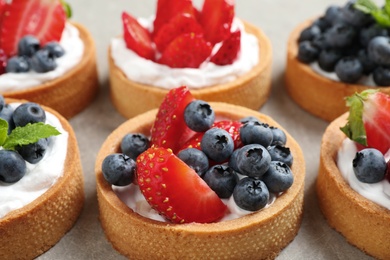 Photo of Delicious sweet pastries with berries on grey table, closeup