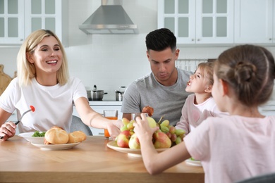 Photo of Happy family having breakfast together at table in modern kitchen