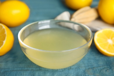 Photo of Freshly squeezed lemon juice in glass bowl on blue table