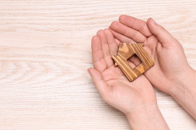 Photo of Home security concept. Man holding house model at wooden table, top view with space for text