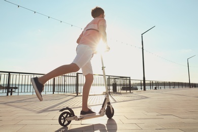 Photo of Man riding modern kick scooter along waterfront