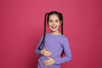 Portrait of little girl laughing on color background