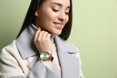 Woman with luxury wristwatch on green background, closeup
