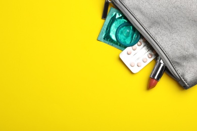 Photo of Flat lay composition with birth control pills and condoms on yellow background, space for text. Safe sex concept