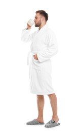 Photo of Handsome man in bathrobe with cup of coffee on white background