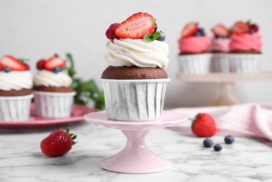 Photo of Delicious cupcake with cream and berries on white marble table