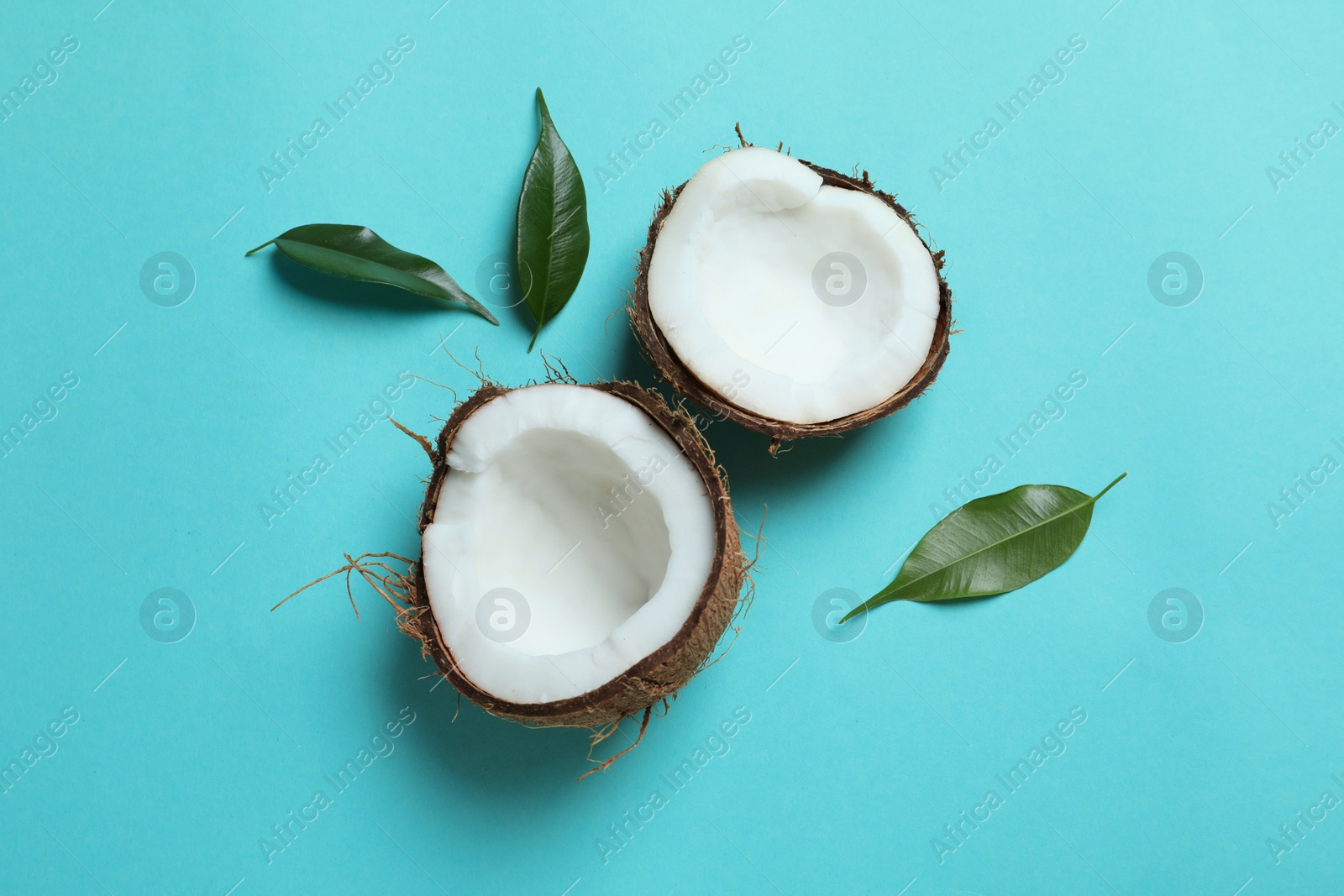 Photo of Coconut halves with leaves on color background