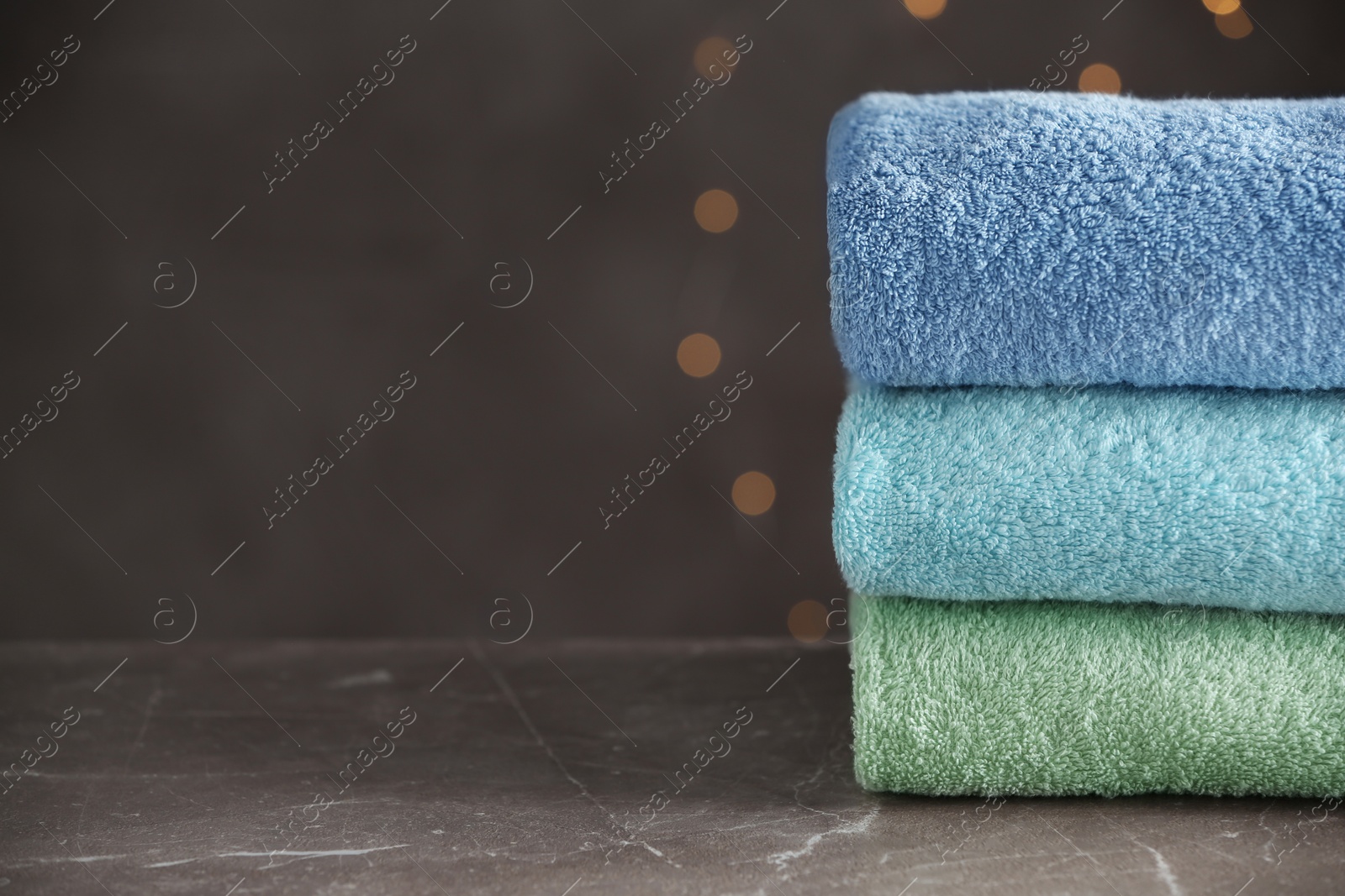 Photo of Stack of clean bath towels on grey table. Space for text