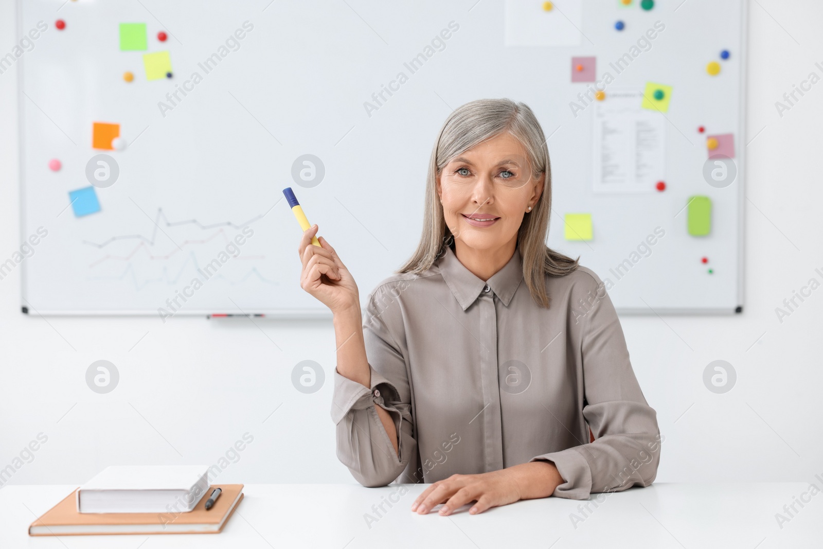 Photo of Happy professor giving lecture at desk in classroom, space for text