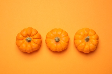 Photo of Fresh ripe pumpkins on orange background, flat lay