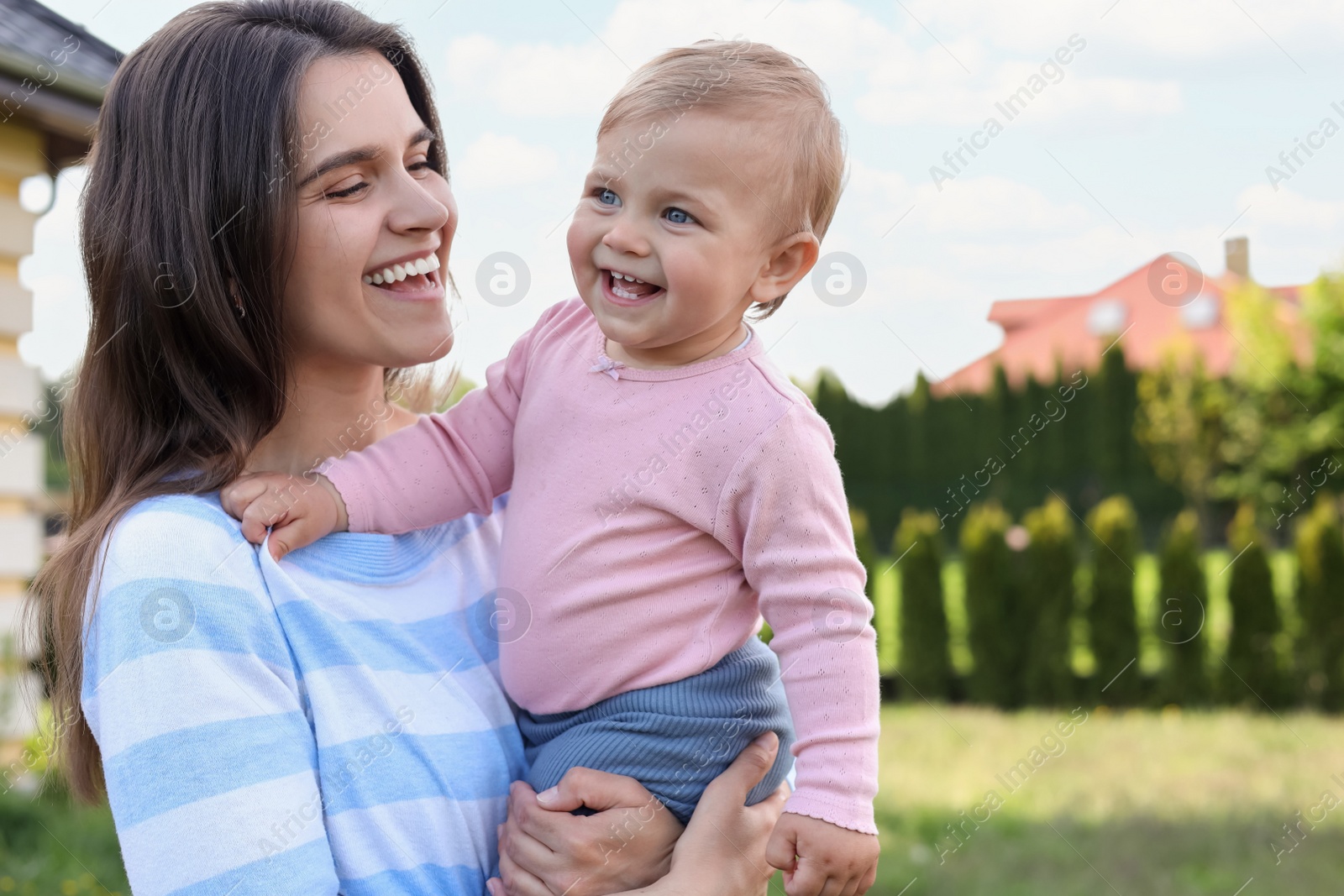 Photo of Happy mother with her cute baby at backyard on sunny day, space for text