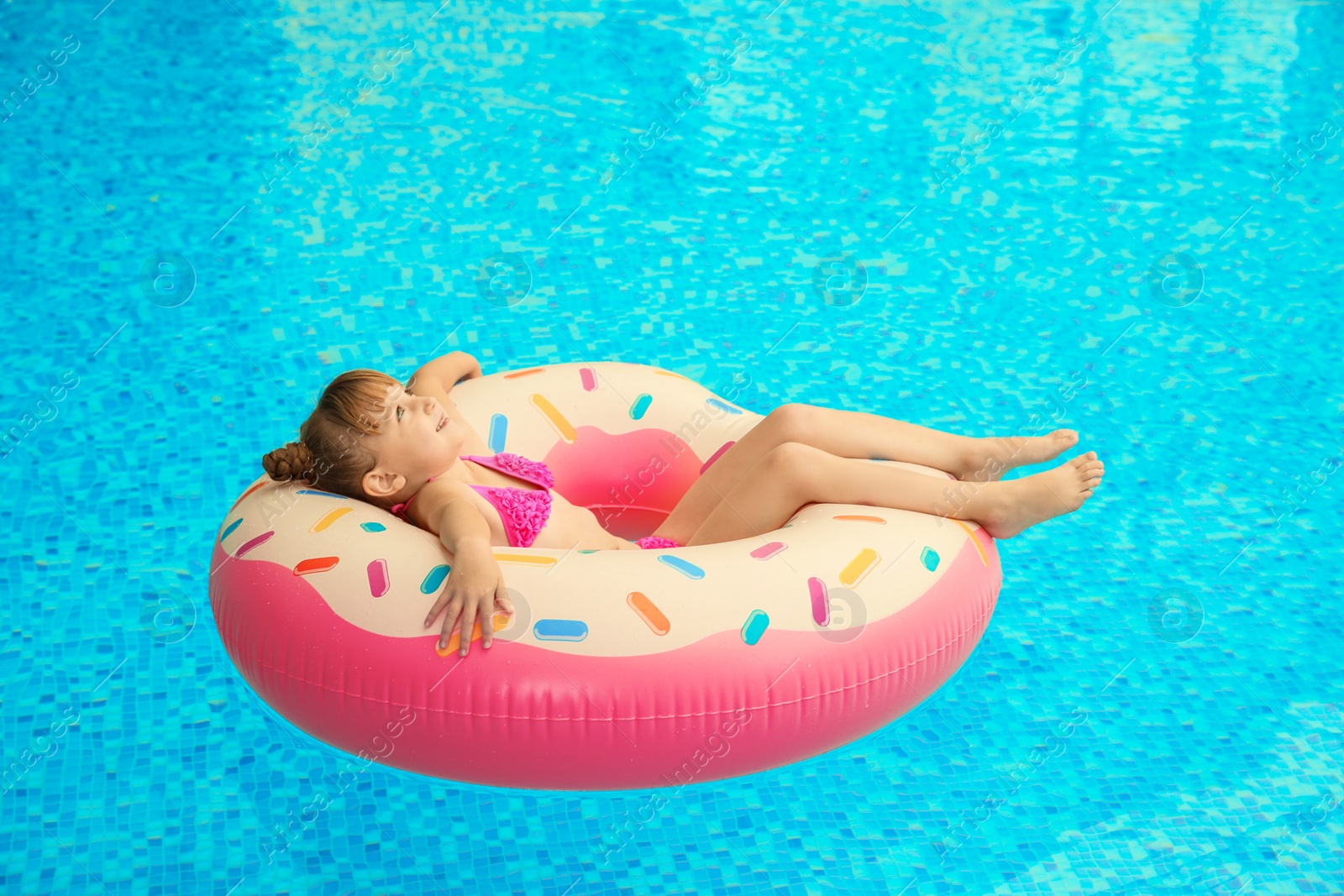 Photo of Happy girl relaxing on inflatable ring in swimming pool