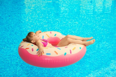 Photo of Happy girl relaxing on inflatable ring in swimming pool